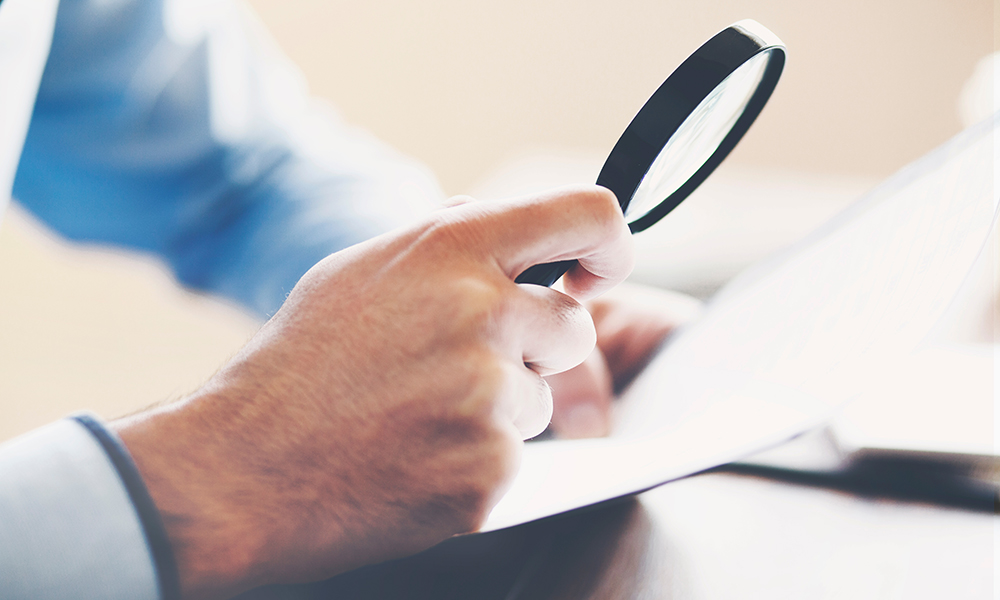 Businessman looking through a magnifying glass to documents